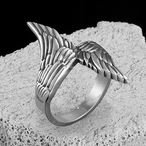 Silver winged ring on a textured stone surface