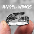Silver angel wing ring held between fingers with 'Angel Wings' text above.