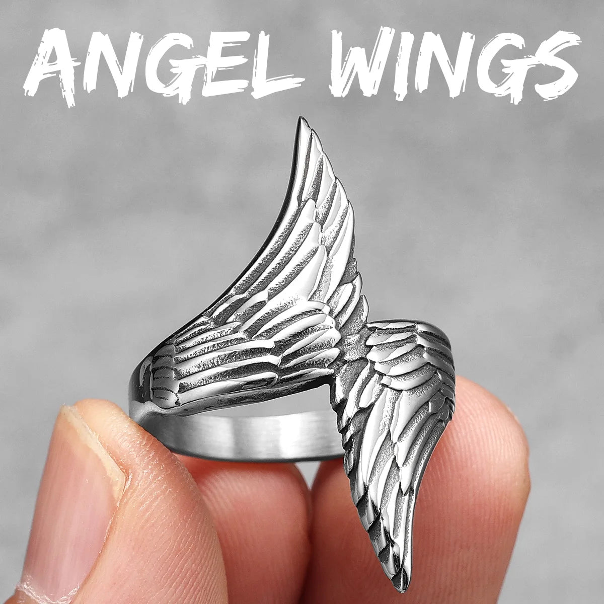 Silver angel wing ring held by a hand against a grey background with 'ANGEL WINGS' text.