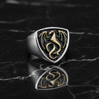 Ring with dragon emblem on a black marble surface
