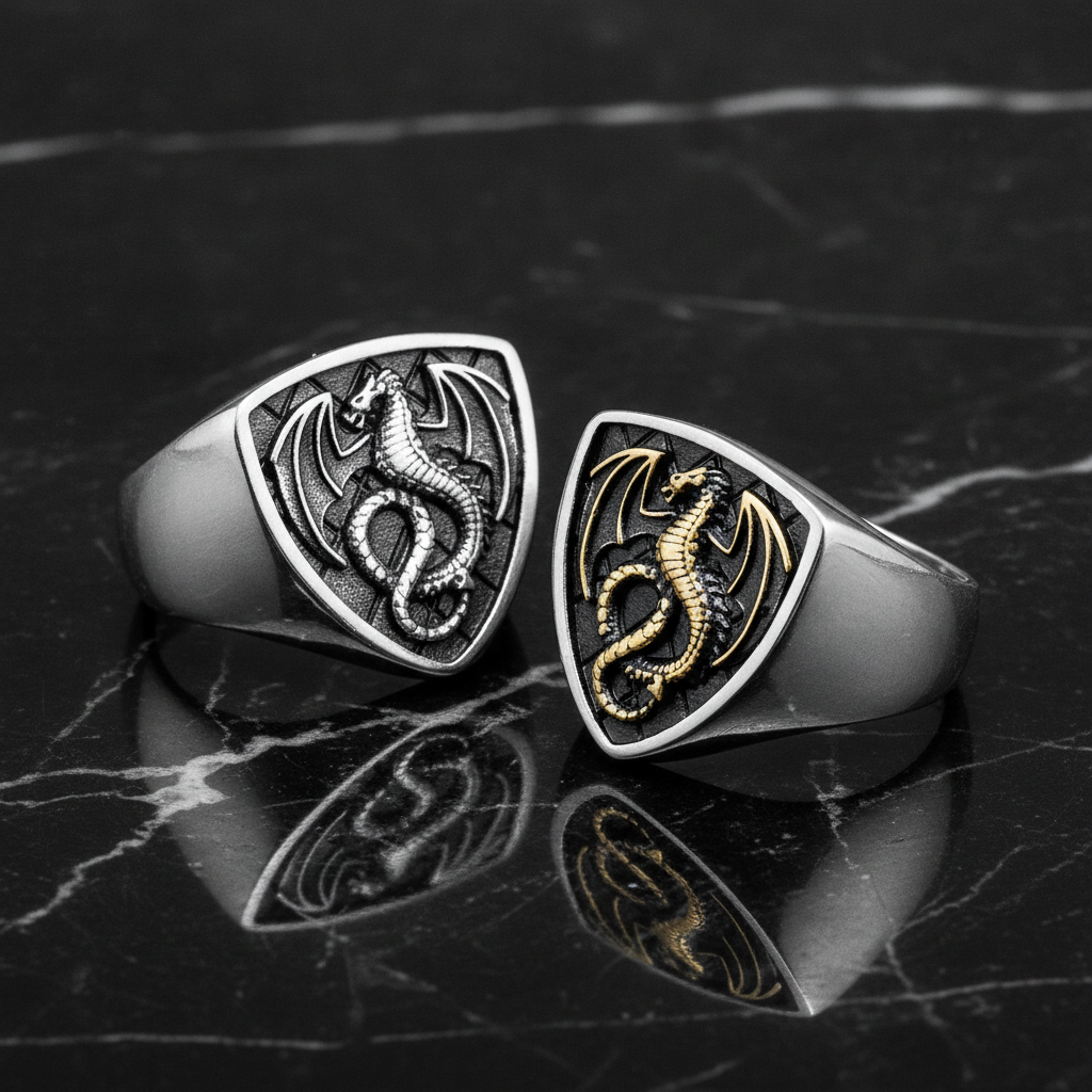 Two dragon-themed rings, one silver and one gold, on a dark marble surface.