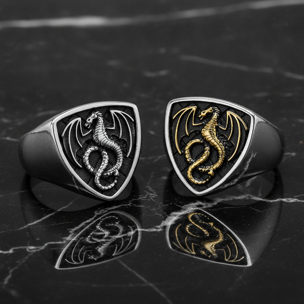 Two dragon-themed silver rings on a reflective black marble surface