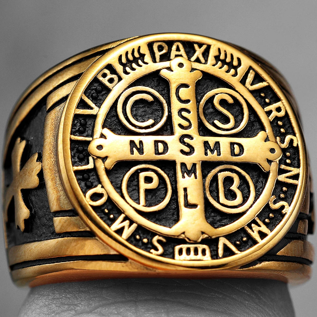 Gold ring with intricate religious design and symbols on a grey background