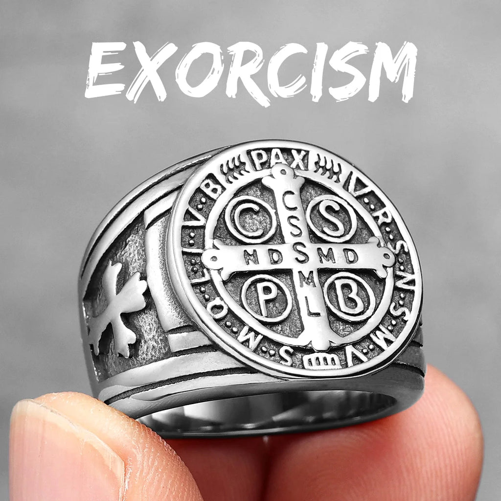 Silver ring with religious symbols held by a hand against a grey background, text 'EXORCISM' above.