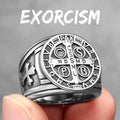 Silver ring with religious symbols held by a hand against a grey background, text 'EXORCISM' above.