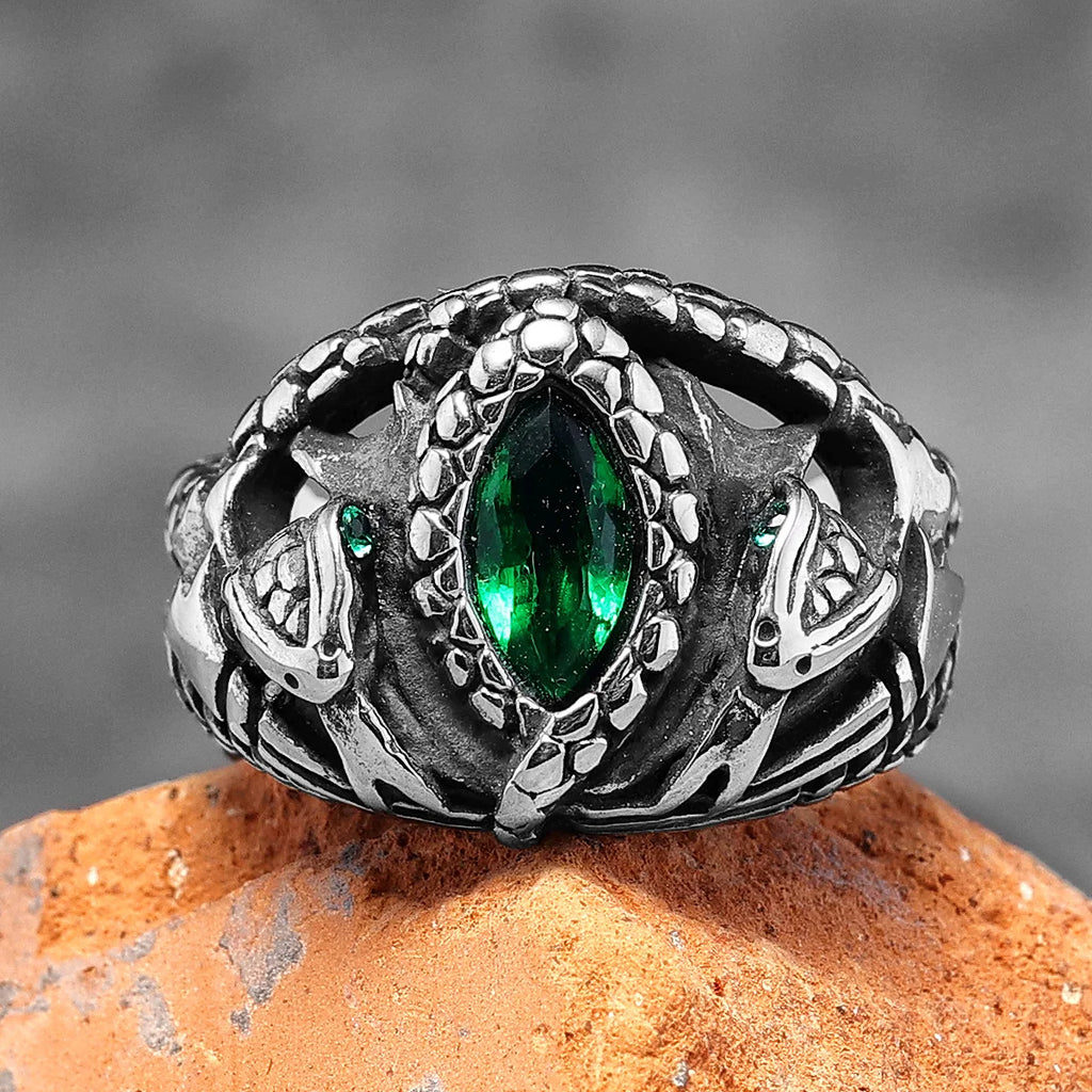 Silver fantasy snake ring with green gemstone on a stone surface