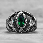 Silver ring with green gemstone on a grey background