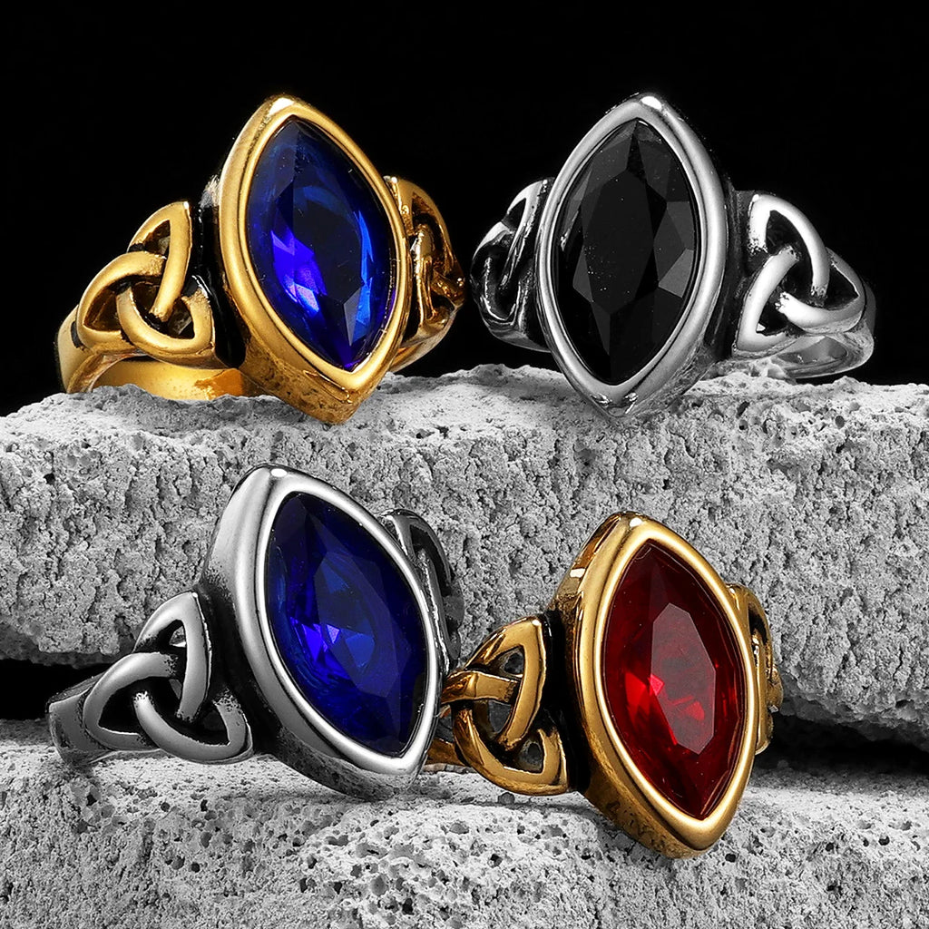 Four rings with different colored gemstones on a stone surface