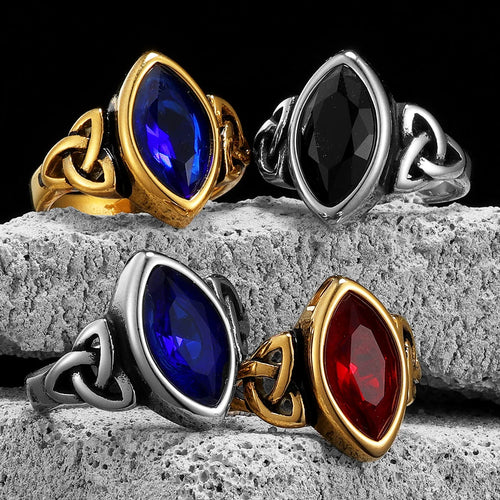 Four rings with different colored gemstones on a stone surface