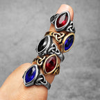 Set of colourful gemstone rings on a finger against a grey background