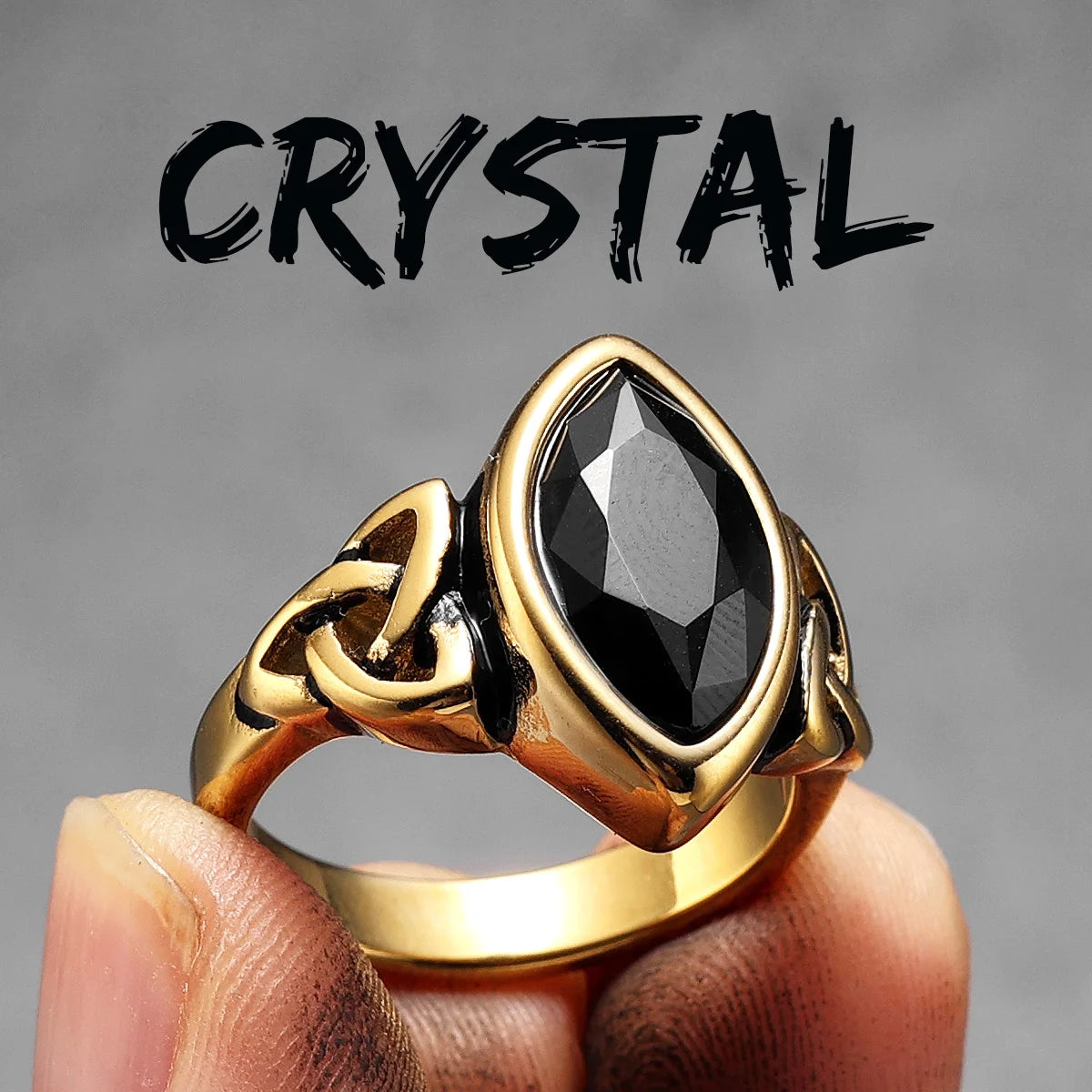 Gold elven ring with a black gemstone held by a hand against a grey background