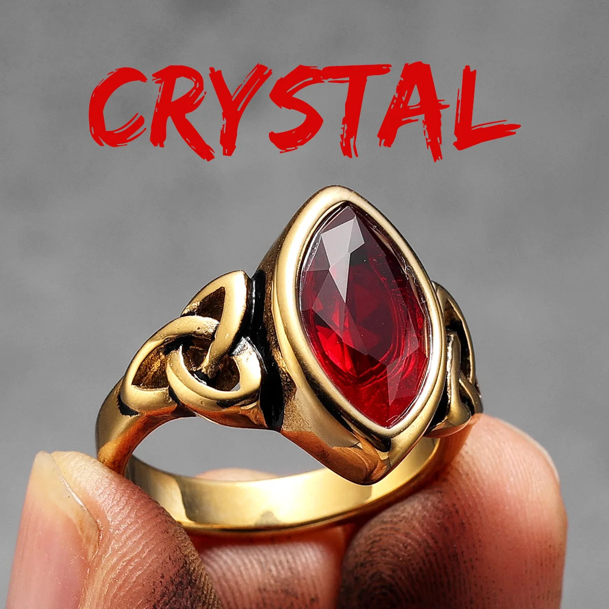 Gold elven ring with a red gemstone held by a hand against a grey background