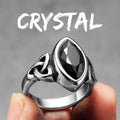 Silver ring with a black gemstone held by a finger against a grey background with 'CRYSTAL' text.