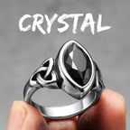 Silver ring with a black gemstone held by a finger against a grey background with 'CRYSTAL' text.