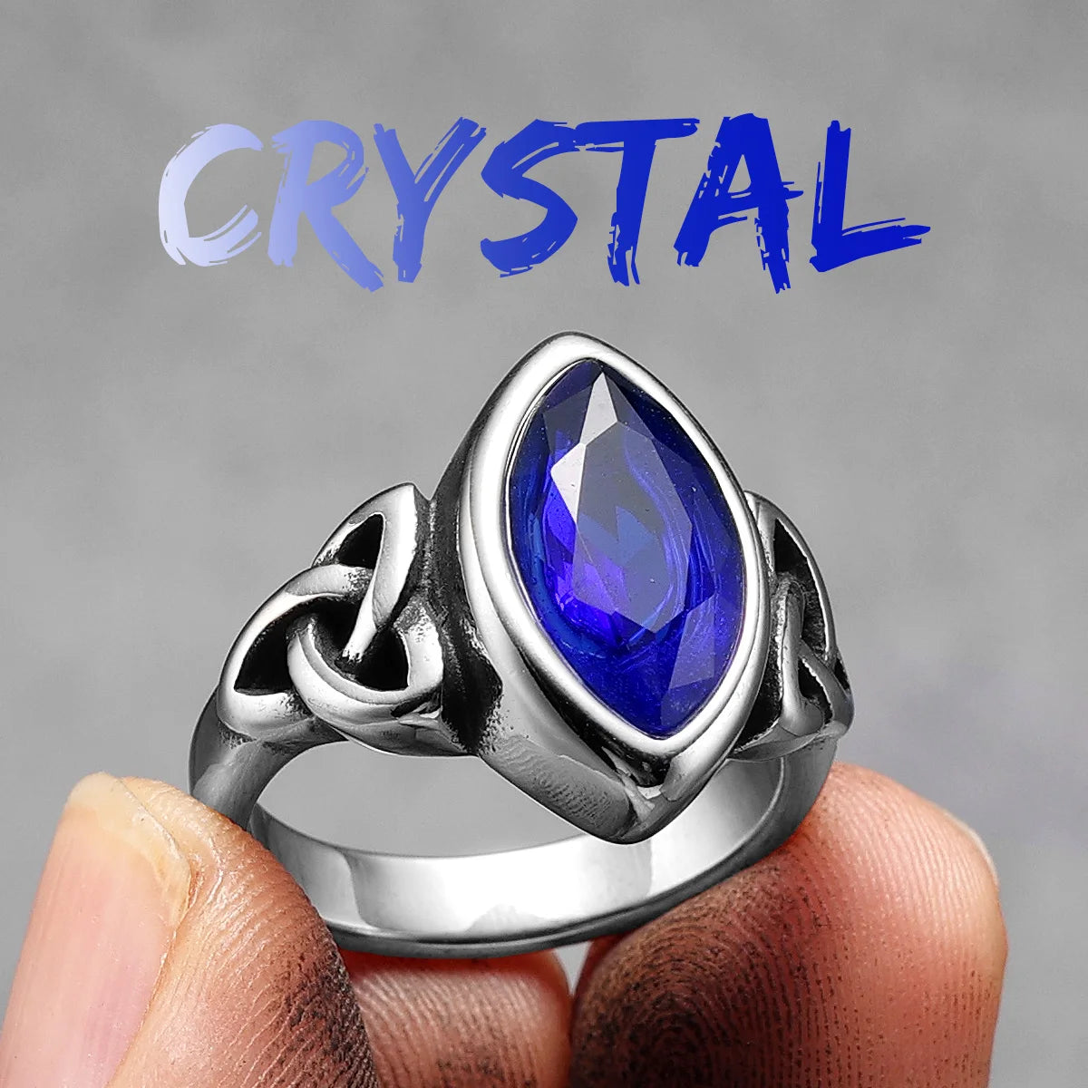 Silver ring with a blue gemstone held in a hand against a gray background