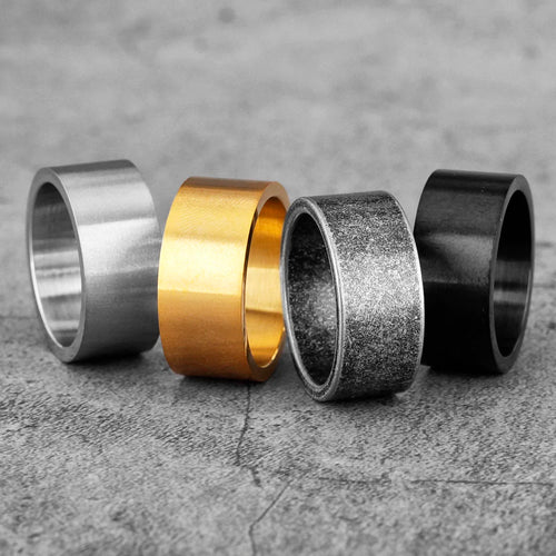 Four metallic rings in different colours on a textured surface