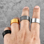 Hand wearing five different rings on a grey background