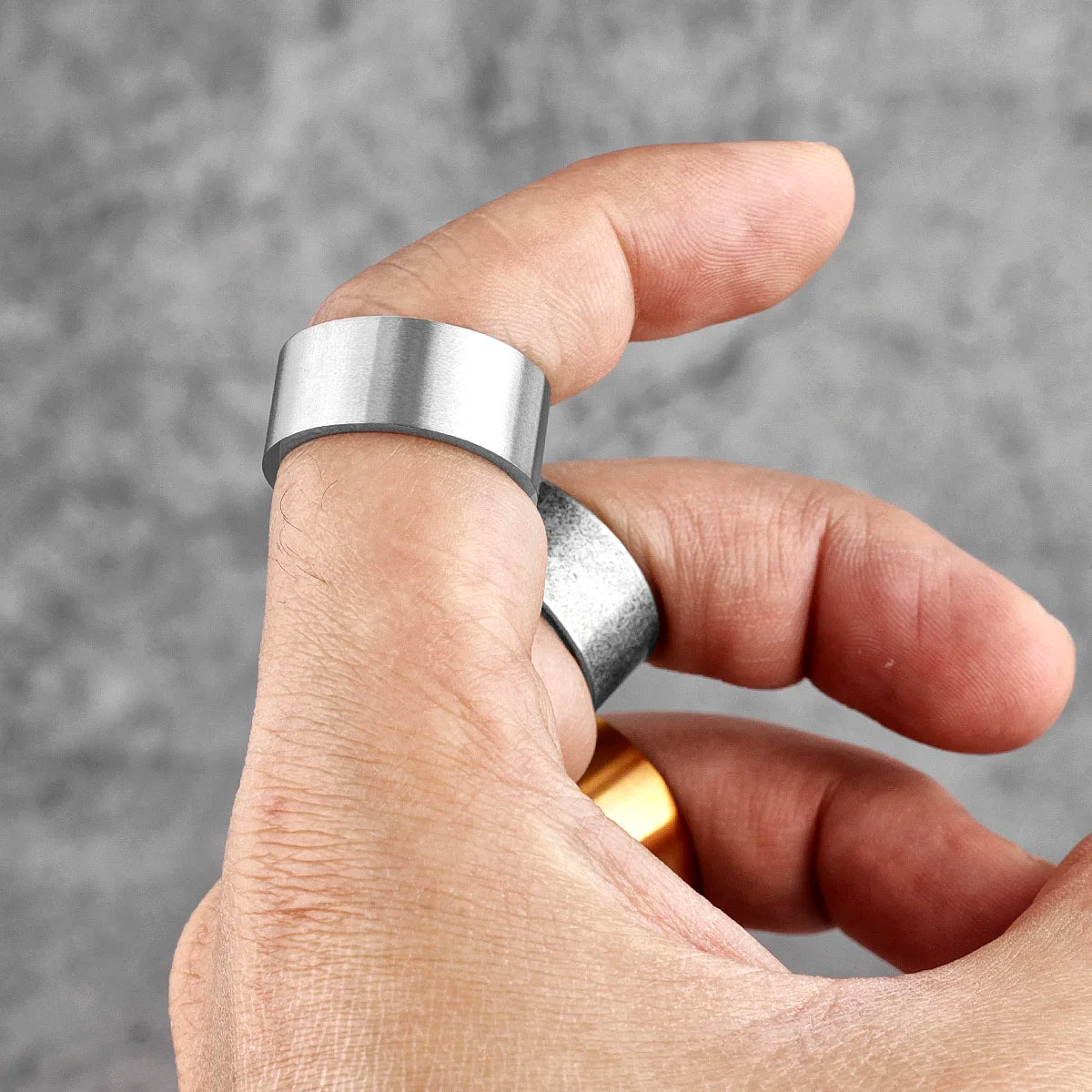 Hand wearing a silver ring with a blurred grey background