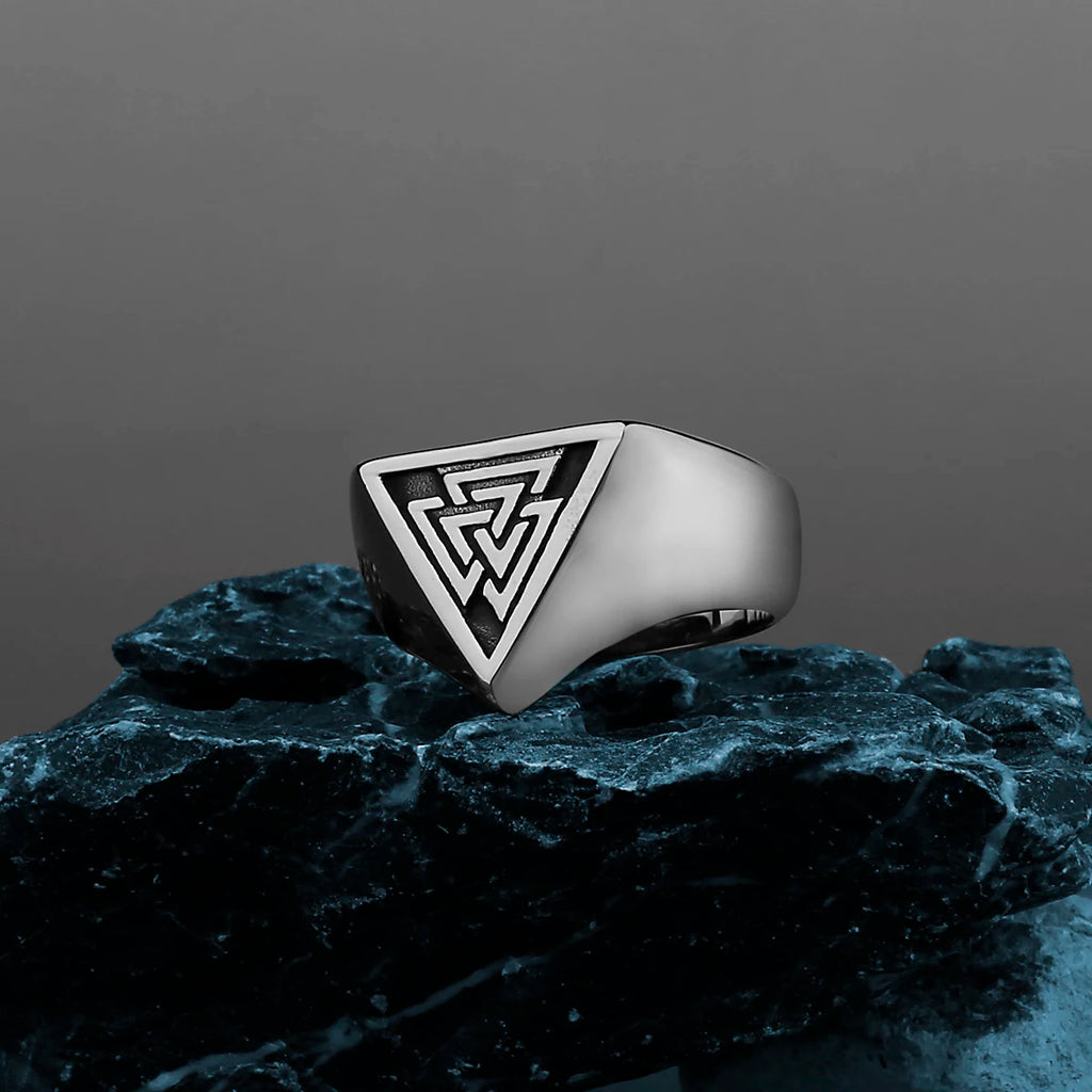 Silver ring with a viking design on a dark stone surface