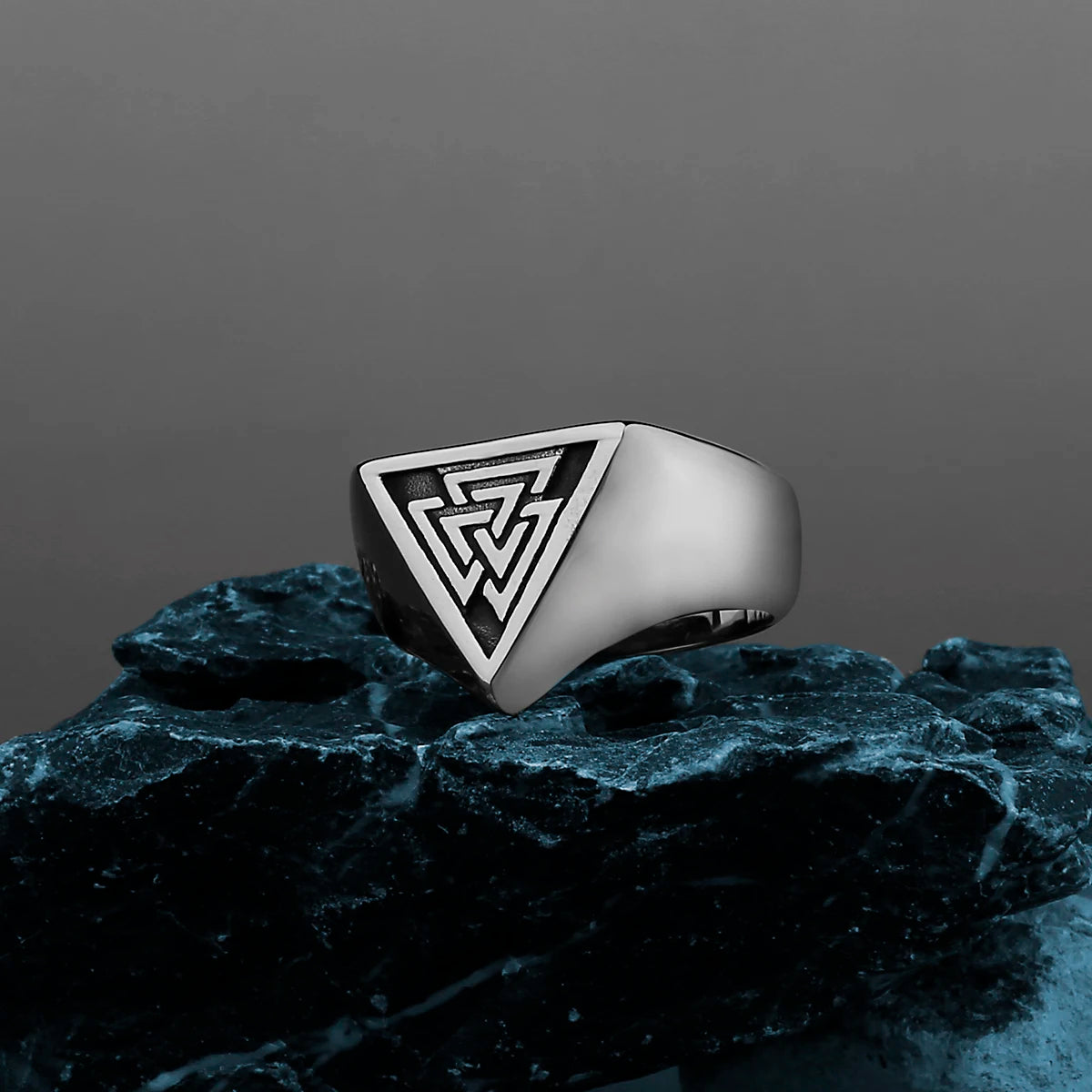 Silver ring with a viking design on a dark stone surface