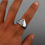 Silver ring with a nordic design on a finger against a grey background
