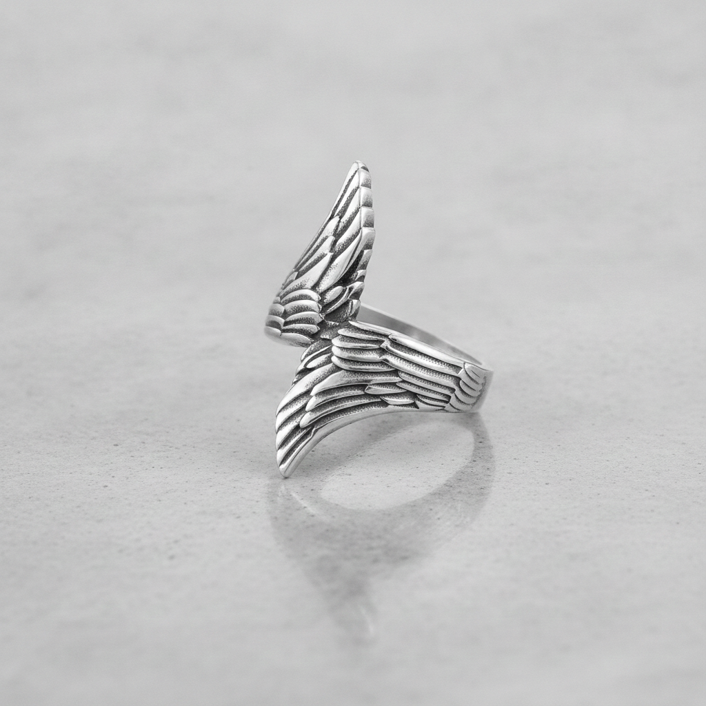 Silver wing-shaped ring on a light grey background