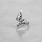 Silver wing-shaped ring on a light grey background