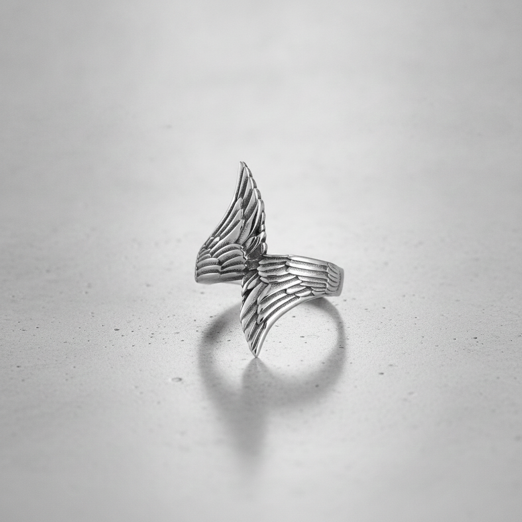 Silver wing-shaped ring on a light grey background