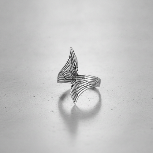 Silver wing-shaped ring on a light grey background