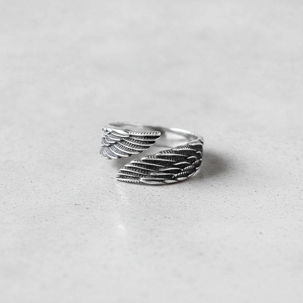 Silver feather-patterned ring on a light grey background