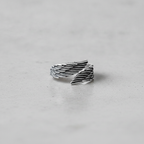 Silver wing-shaped ring on a light grey background