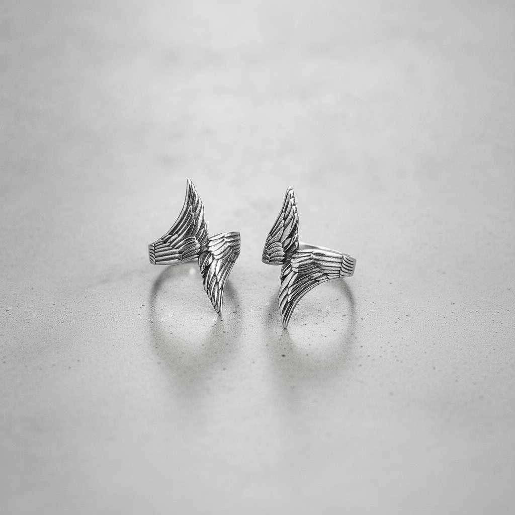 Pair of silver rings with a angel wing design on a light grey background