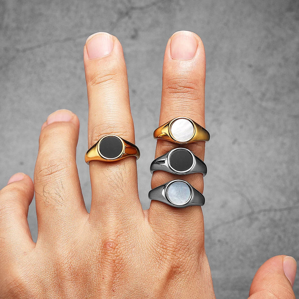 Hand wearing four gold and silver rings on a grey background