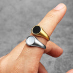Two pearl rings, one gold and one silver, on a finger against a grey background