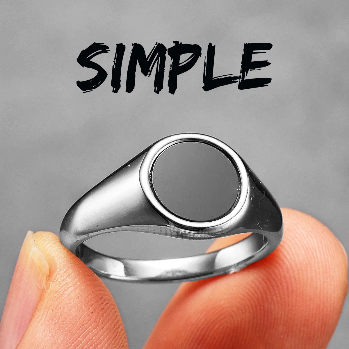 Silver ring with a black centre on a finger, against a grey background with the word 'SIMPLE' above.