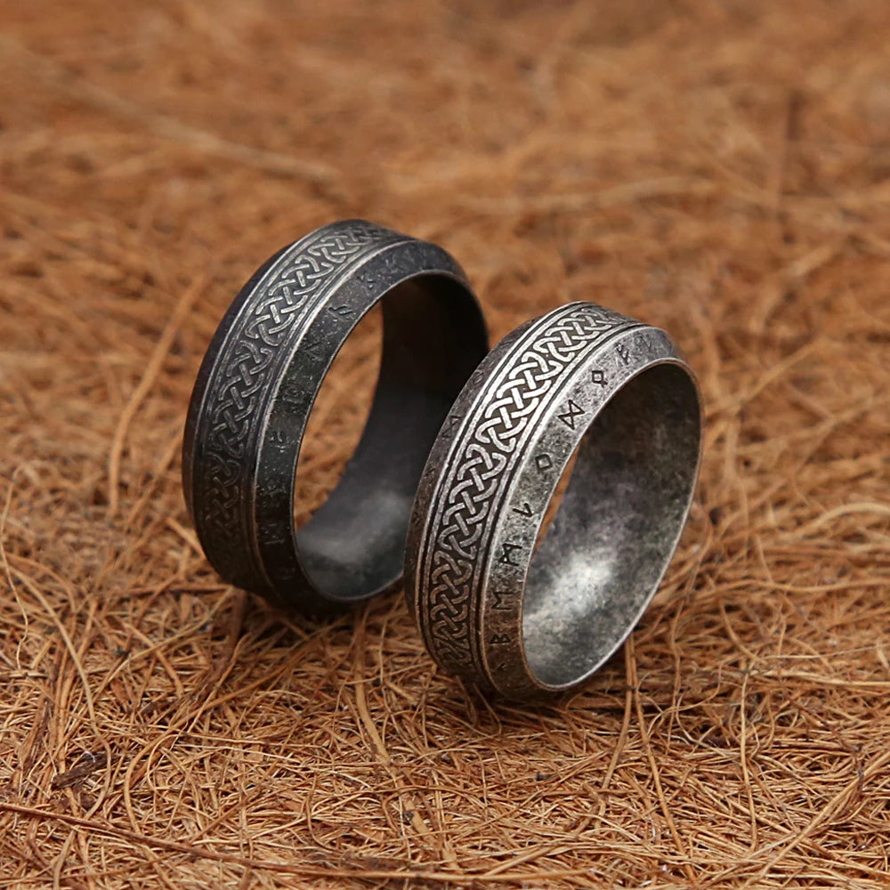 Two silver rings with intricate nordic knot designs on a textured brown surface