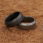 Two metallic rings with intricate designs on a textured brown surface