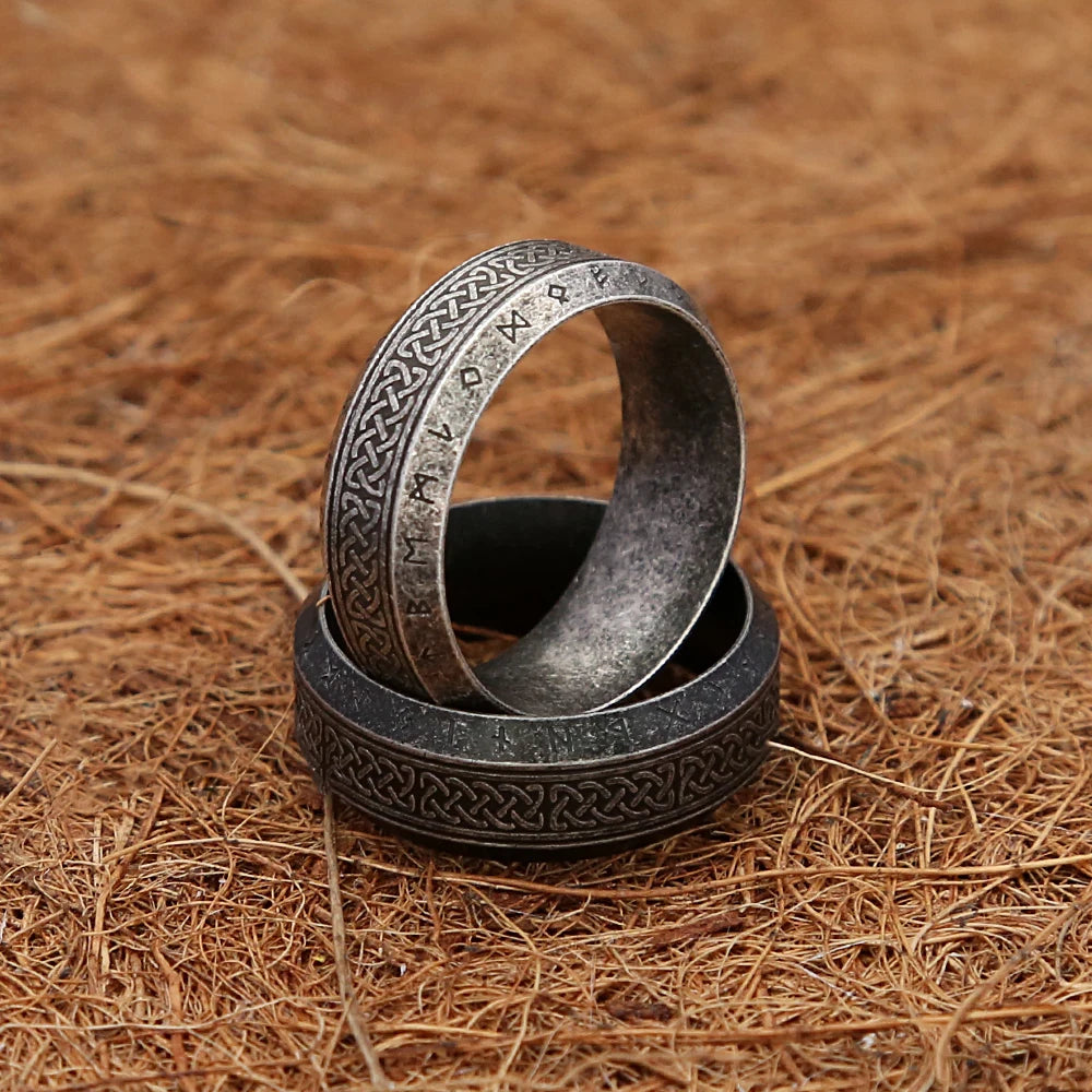 Two silver rings with intricate Viking designs on a brown, straw-like background