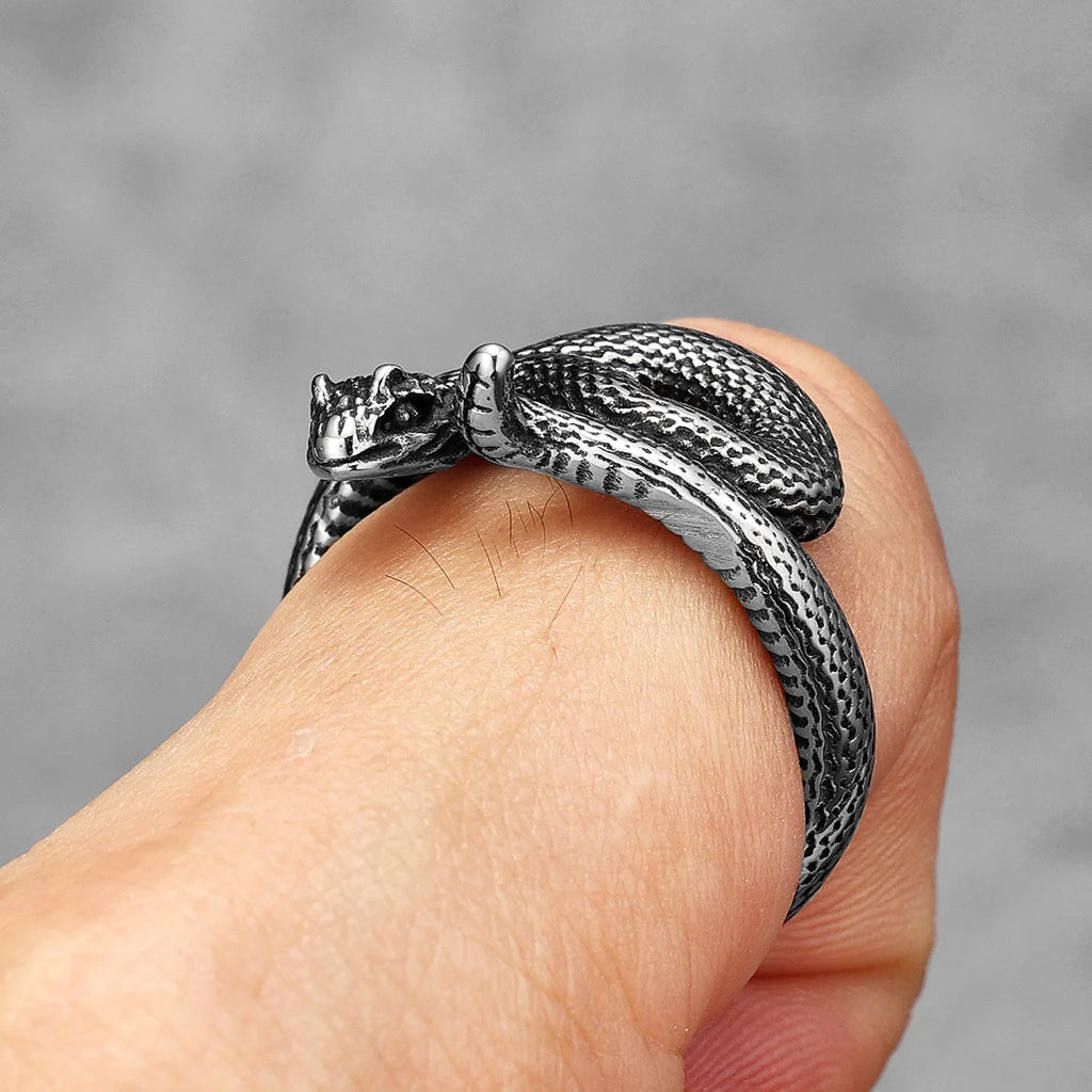Silver snake-shaped ring on a finger against a grey background