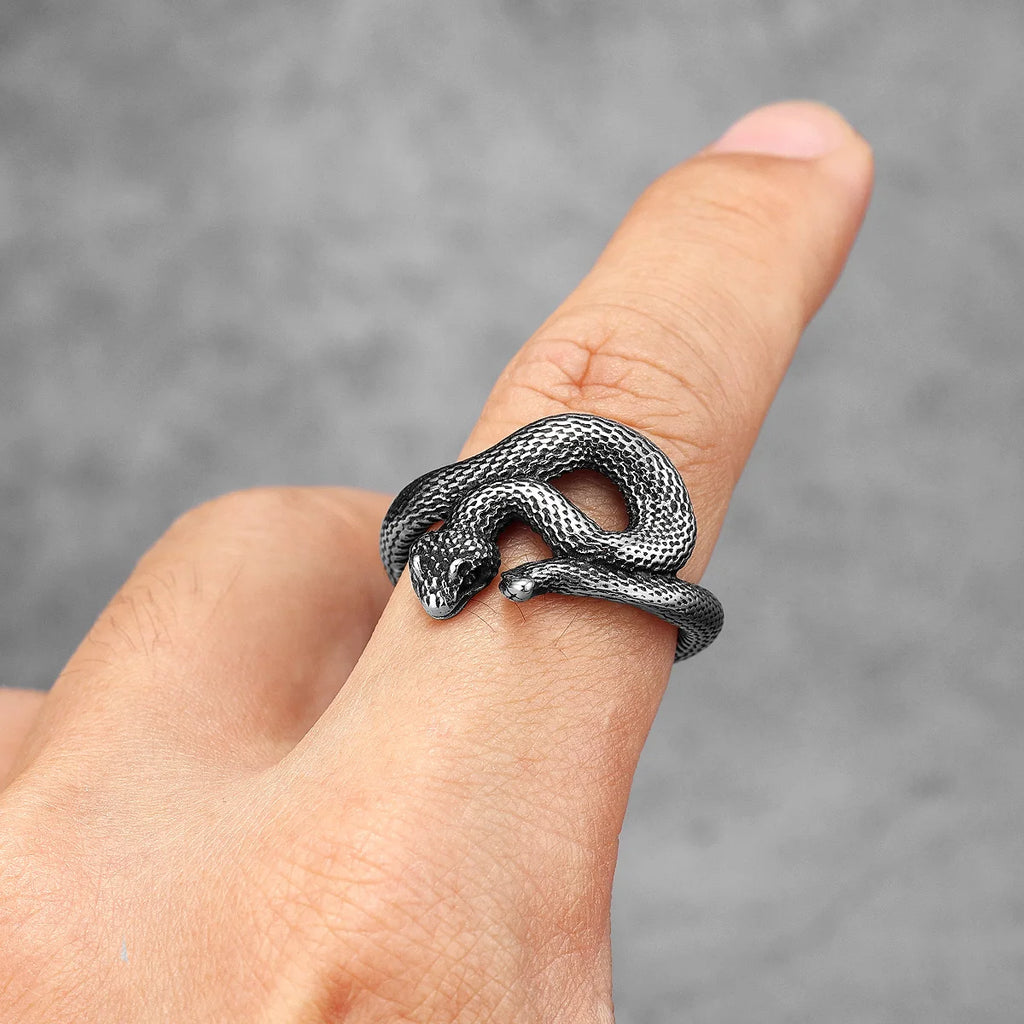 Silver snake-shaped ring on a finger against a grey background