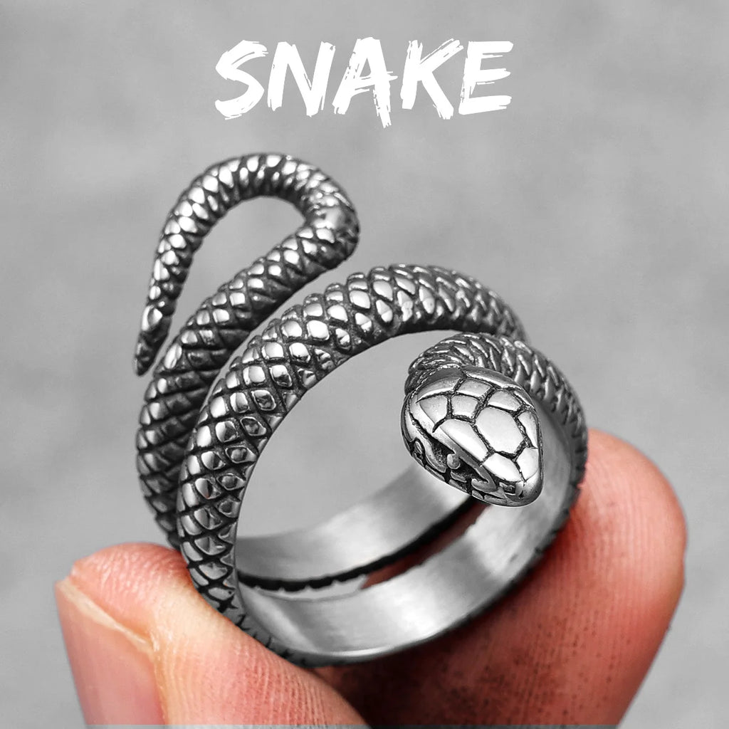 Silver snake-shaped detailed ring held in a hand with a grey background