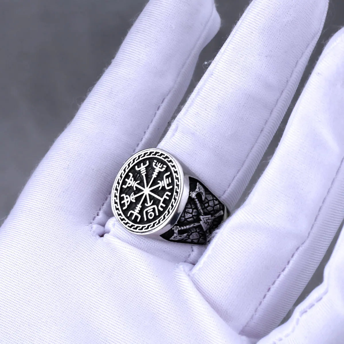 Silver ring with intricate Norse design on a white glove