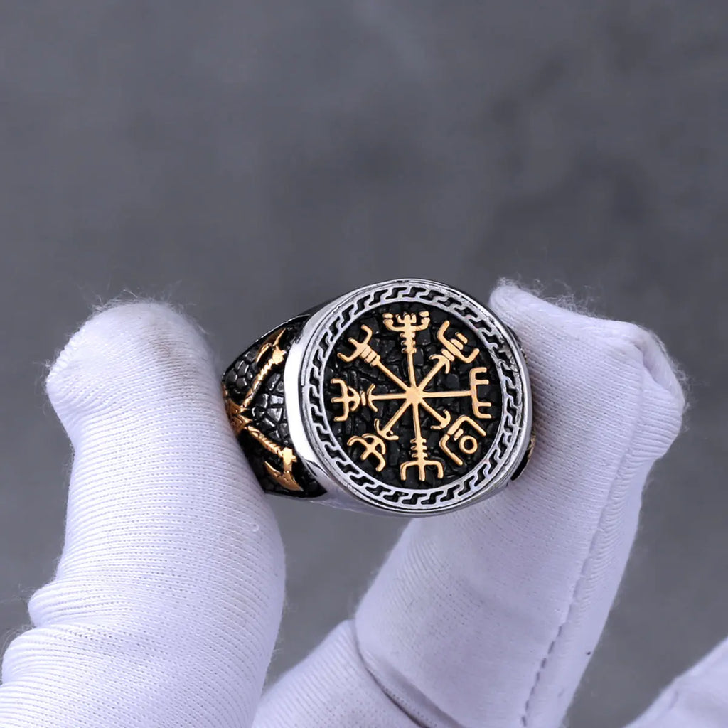 Norse compass silver and gold ring between white gloved fingers