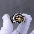 Norse compass silver and gold ring between white gloved fingers