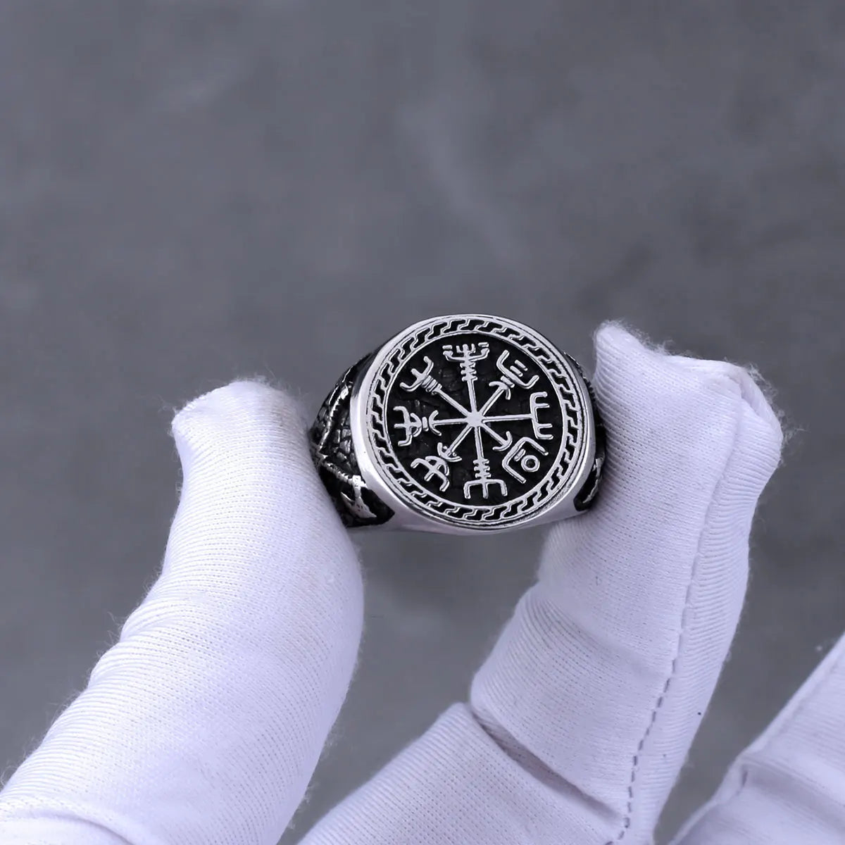 Silver Viking compass ring between white gloved fingers