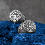 Two silver symbolic compass rings on a textured blue and gray background