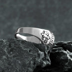 Silver ring with a floral design on a dark stone surface