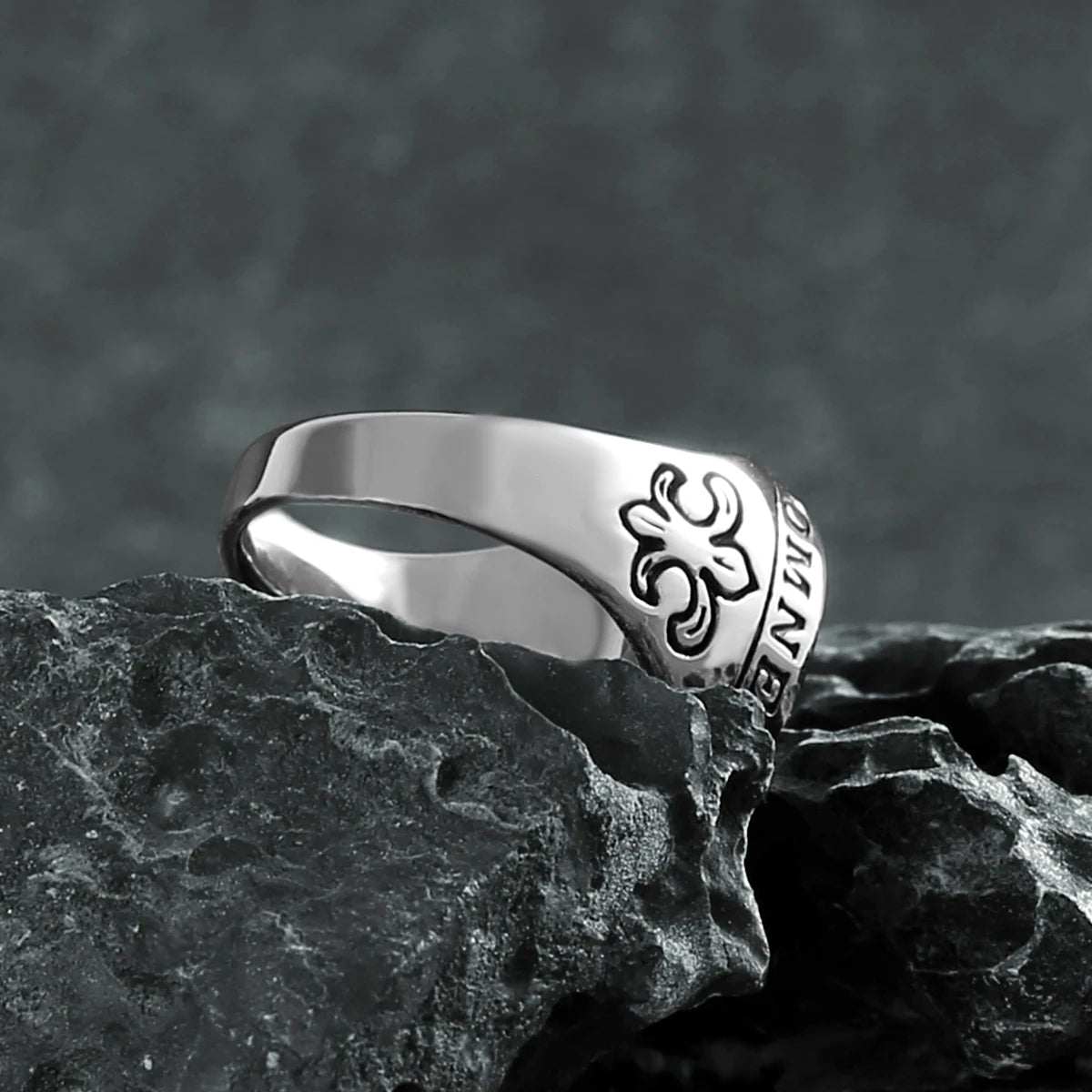 Silver ring with a floral design on a dark stone surface