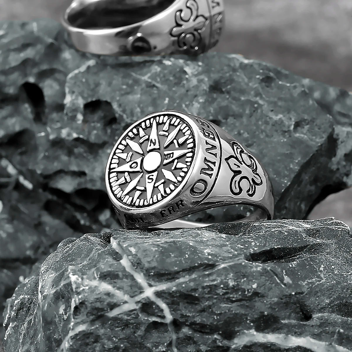 Silver ring with compass design on a textured stone surface