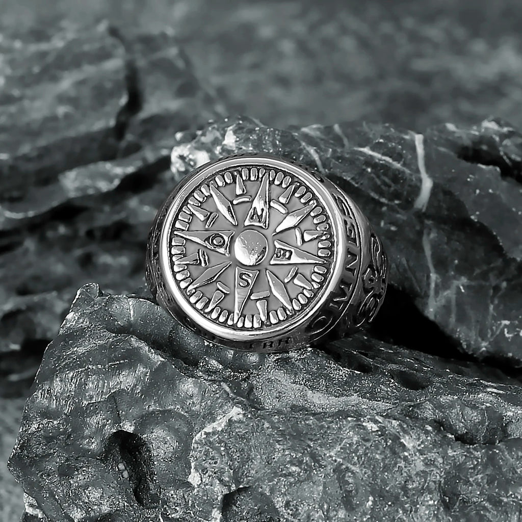 Silver symbolic stainless steel compass ring on a textured stone surface